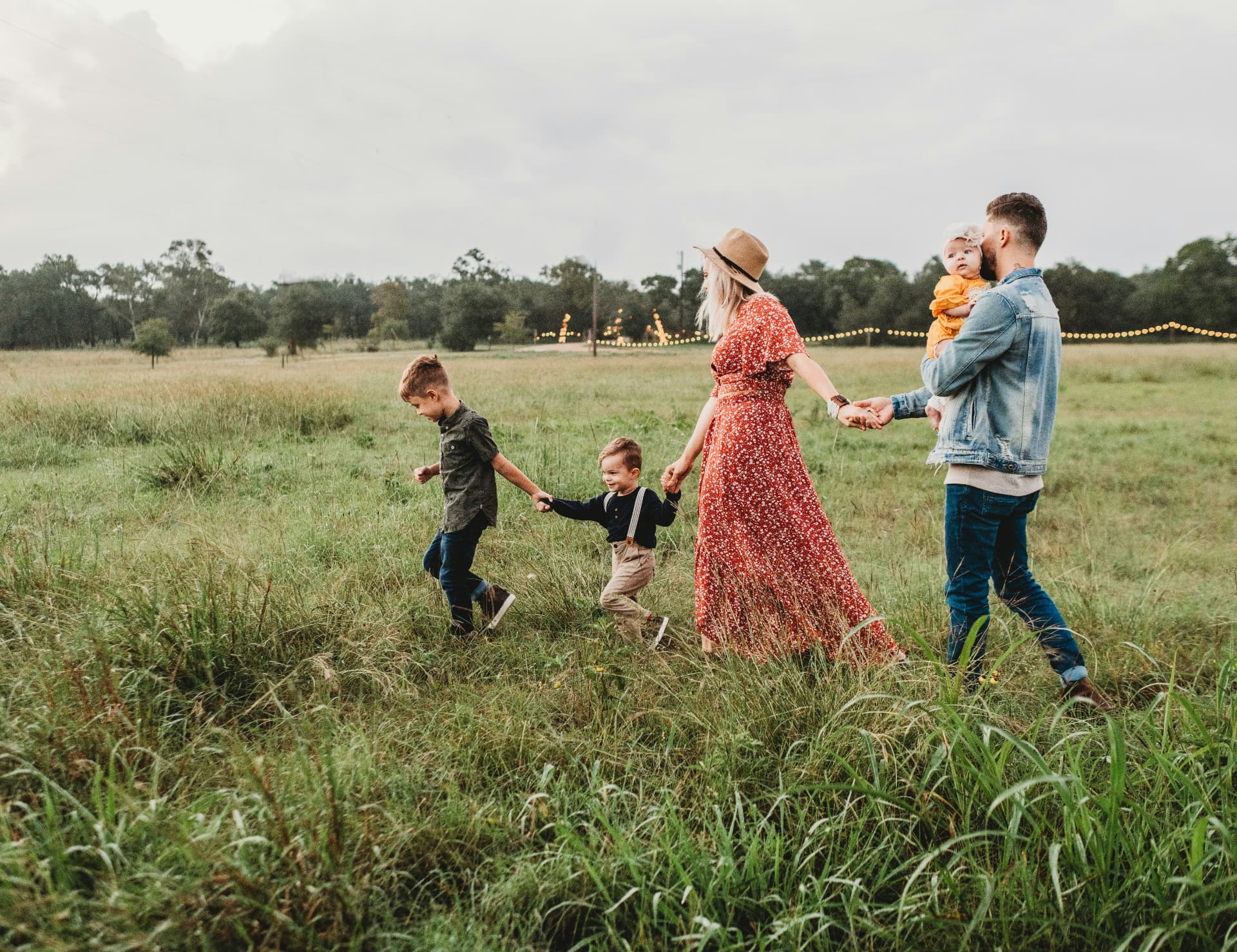 A family walking hand in hand through a grassy field at dusk
